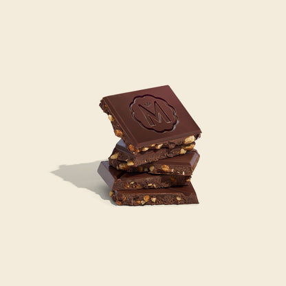 Milk chocolate bar pieces stacked, dark chocolate with visible nuts and caramel bits
