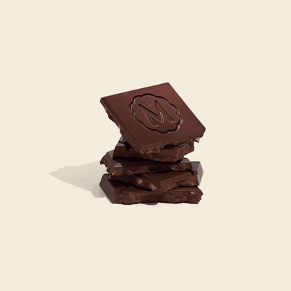 Stacked Marou dark chocolate pieces with embossed logo and popped rice texture
